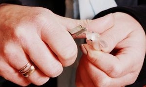 Zwei Hände halten einen Haustürschlüssel und einen kleinen durchsichtigen Plastikchip.